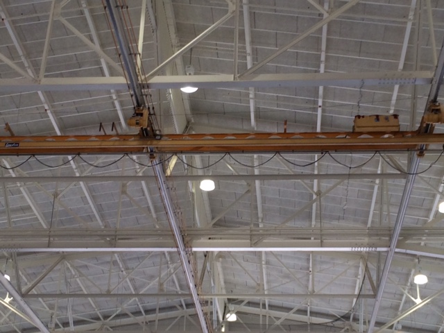 Bird exclusion netting beneath roof trusses and around overhead equipment in a Fort Rucker hangar