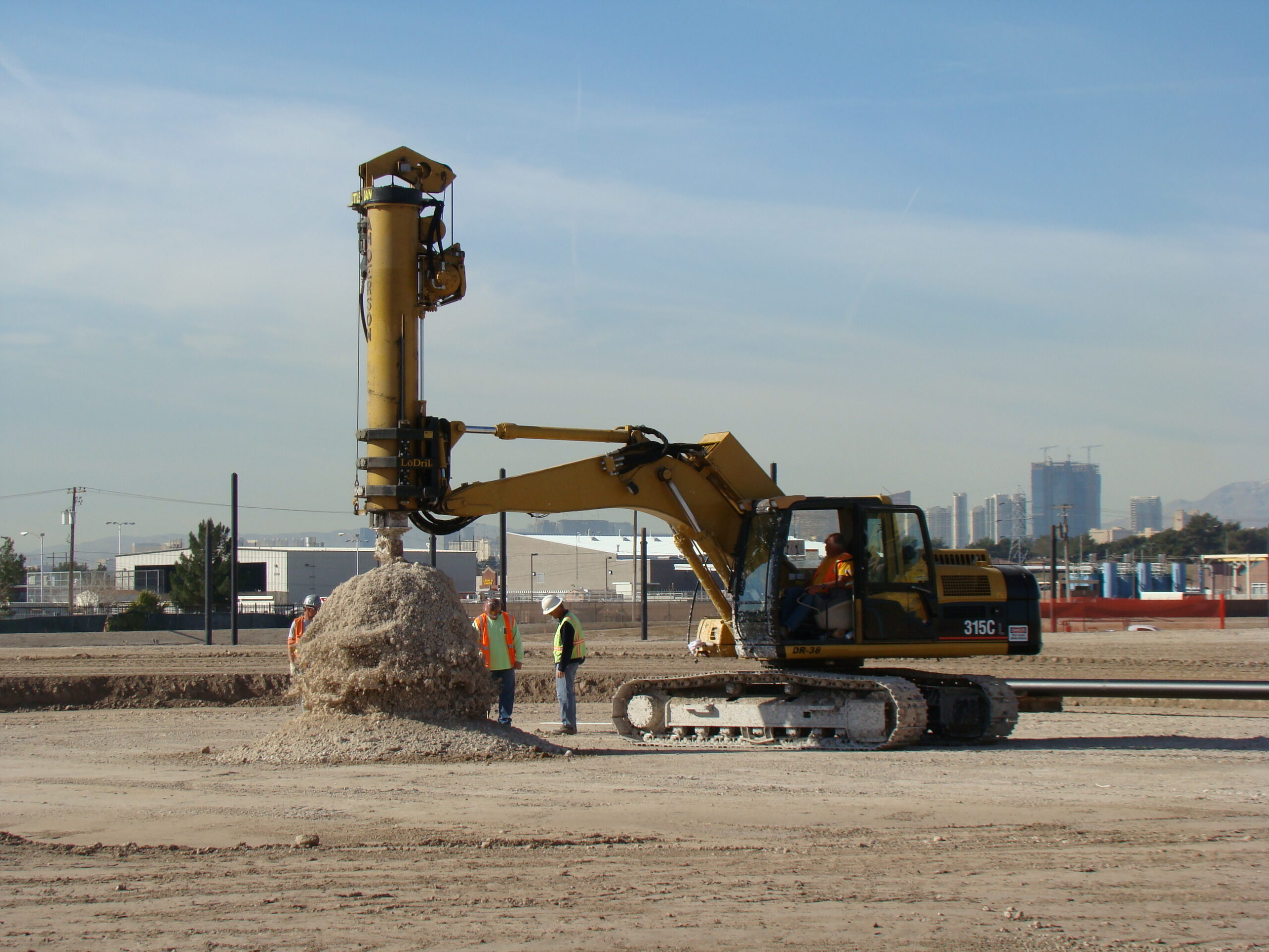 Crew and drilling rig preparing a foundation at an outdoor installation site